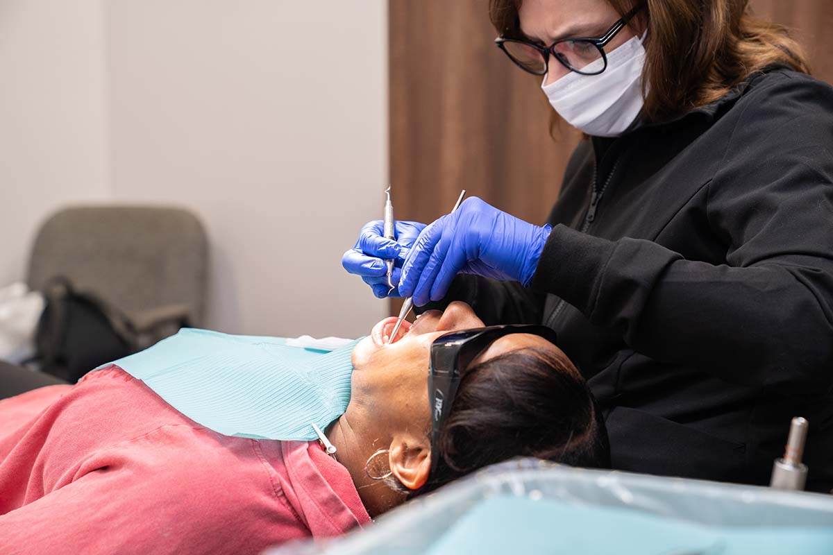 A dentist works on someone's teeth